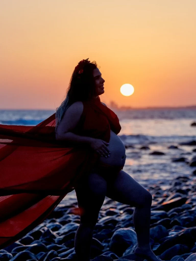 Silueta de embarazada con tela roja al atardecer