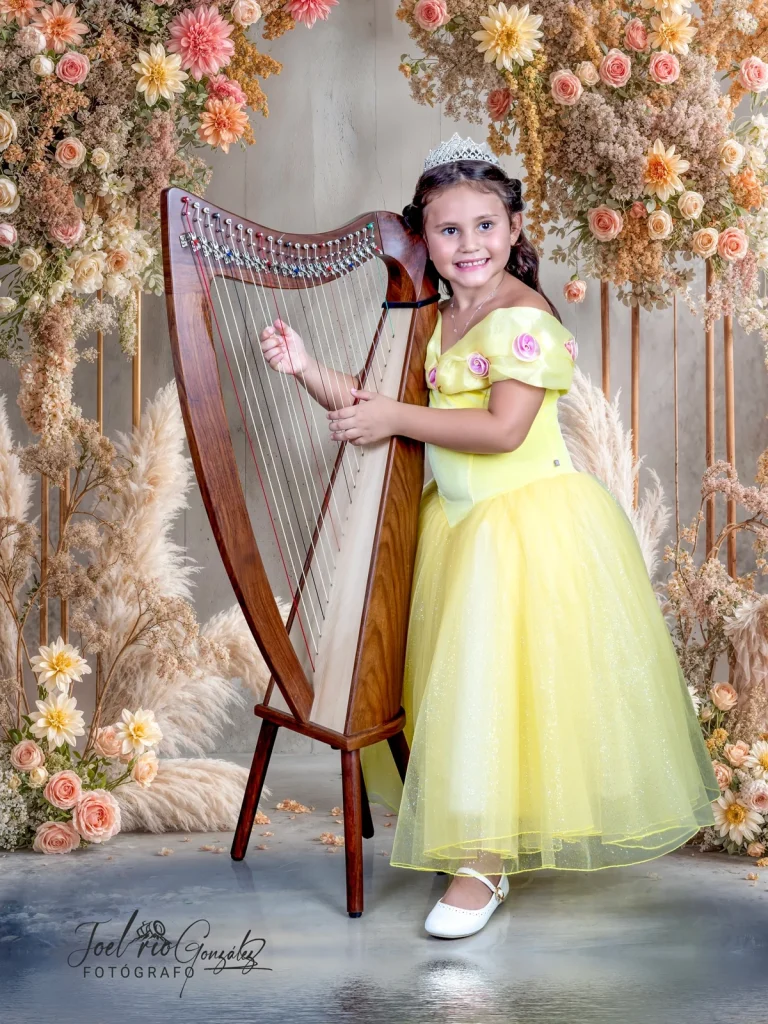 Niña con vestido amarillo junto a un arpa en el estudio
