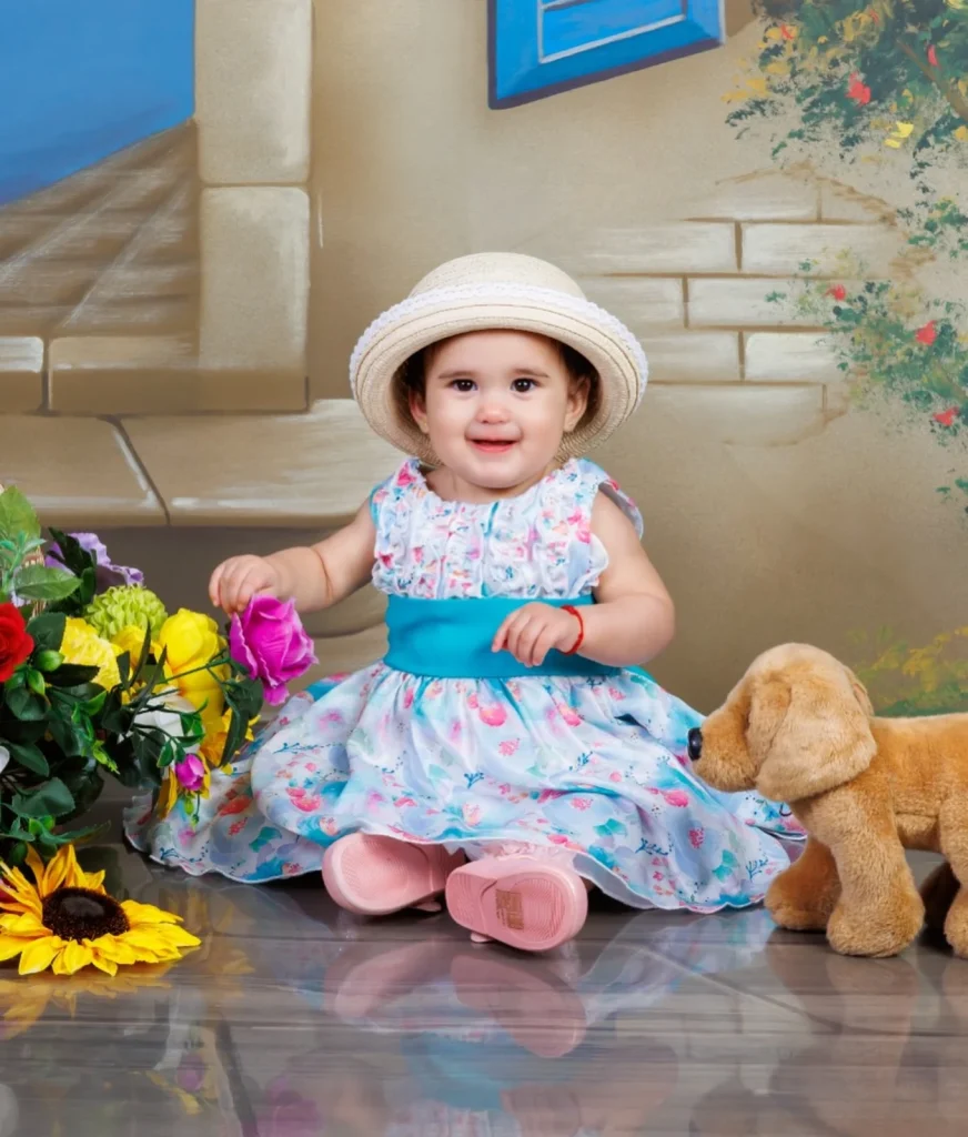 Bebé con sombrero rosa sentada sobre una maleta