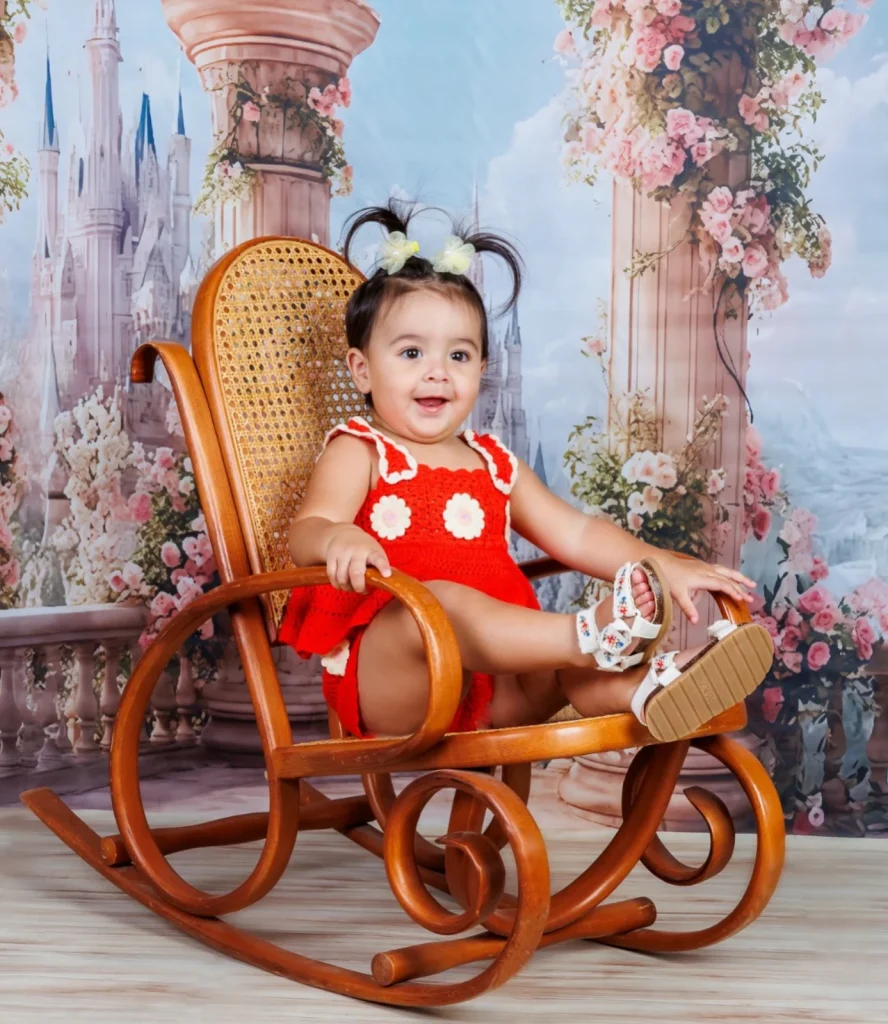 Niña con vestido rojo en una mecedora del estudio