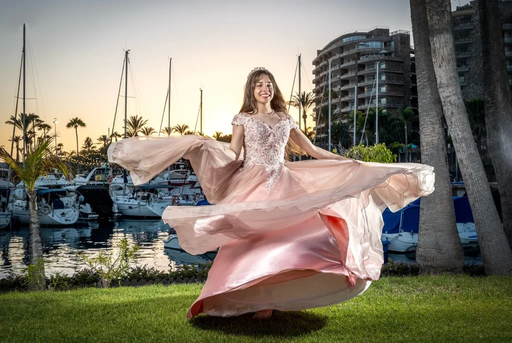 Quinceañera con vestido rosa en movimiento frente a una marina de Gran Canaria