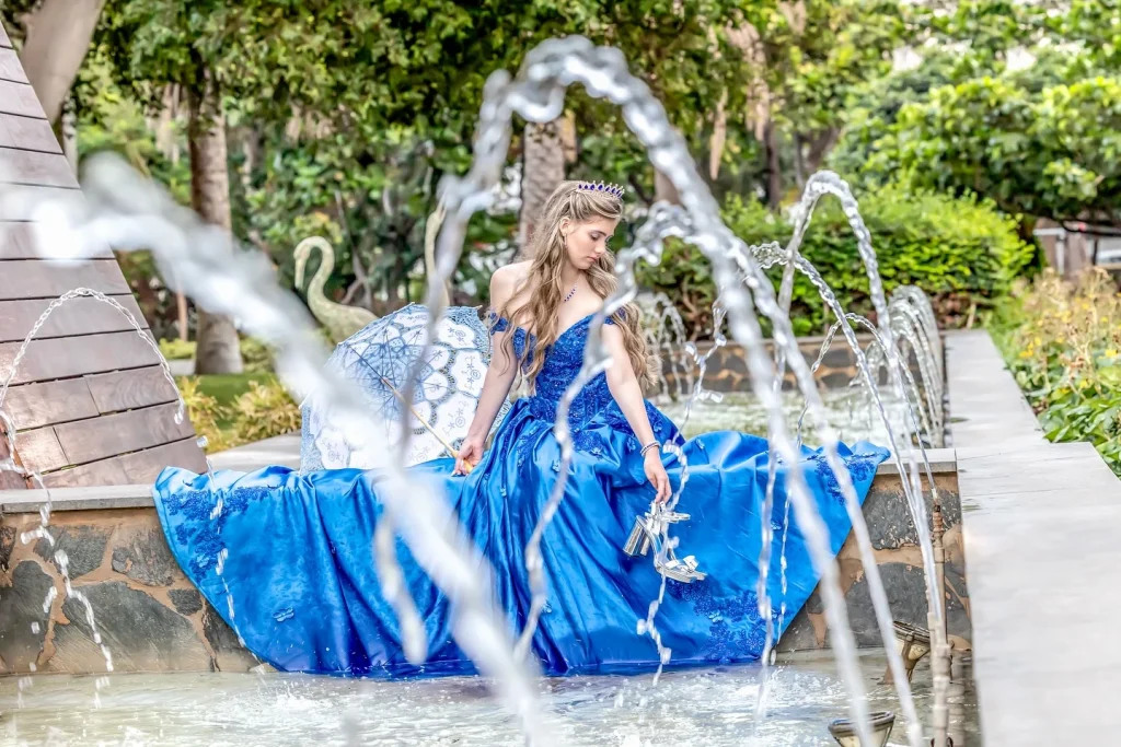 Quinceañera con vestido azul junto a los chorros de una fuente