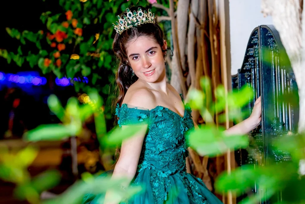 Retrato de quinceañera con vestido verde entre ramas