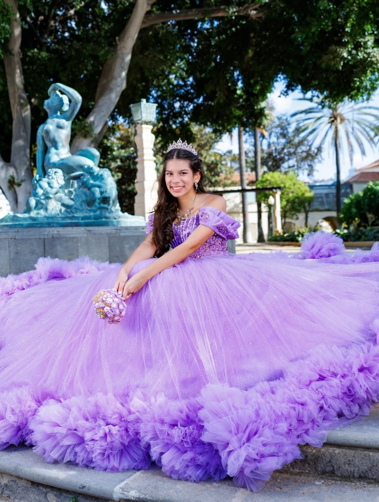 Quinceañera con vestido lila junto a una fuente en Gran Canaria