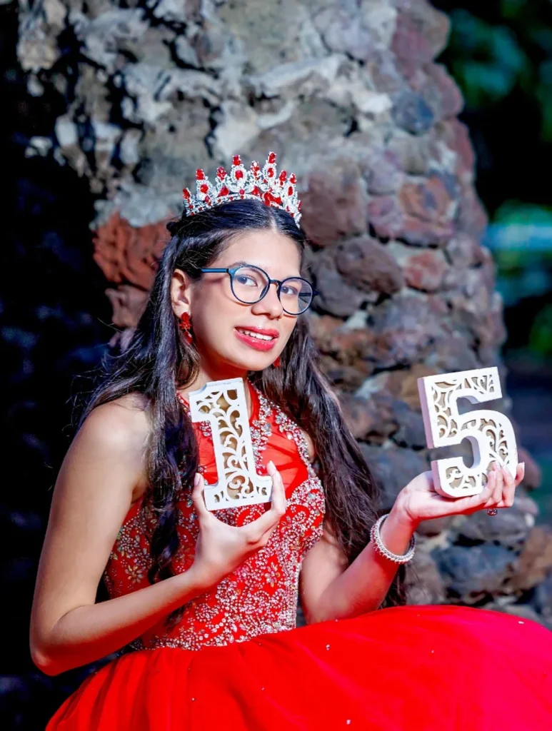 Quinceañera con vestido rojo, corona y números de quince años